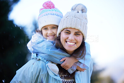 Buy stock photo Shot of an attractive young woman giving her daughter a piggyback ride outside in the rain