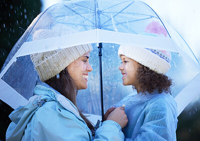 Buy stock photo Shot of an attractive young woman bonding with her daughter outside in the rain