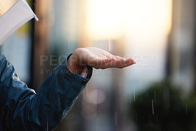 Buy stock photo Shot of an unrecognizable person holding out their hand to feel the rain in the city