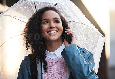 Buy stock photo Shot of a young woman on a call while holding an umbrella in the city