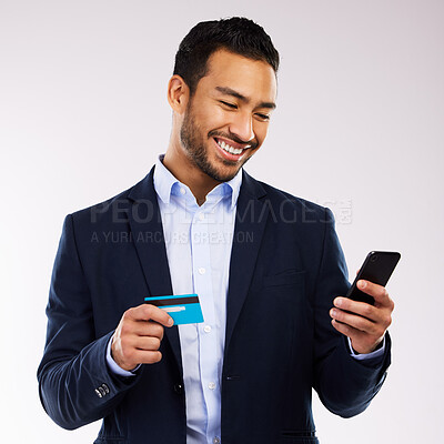 Buy stock photo Shot of a handsome businessman standing against a grey studio background and using his cellphone for online shopping