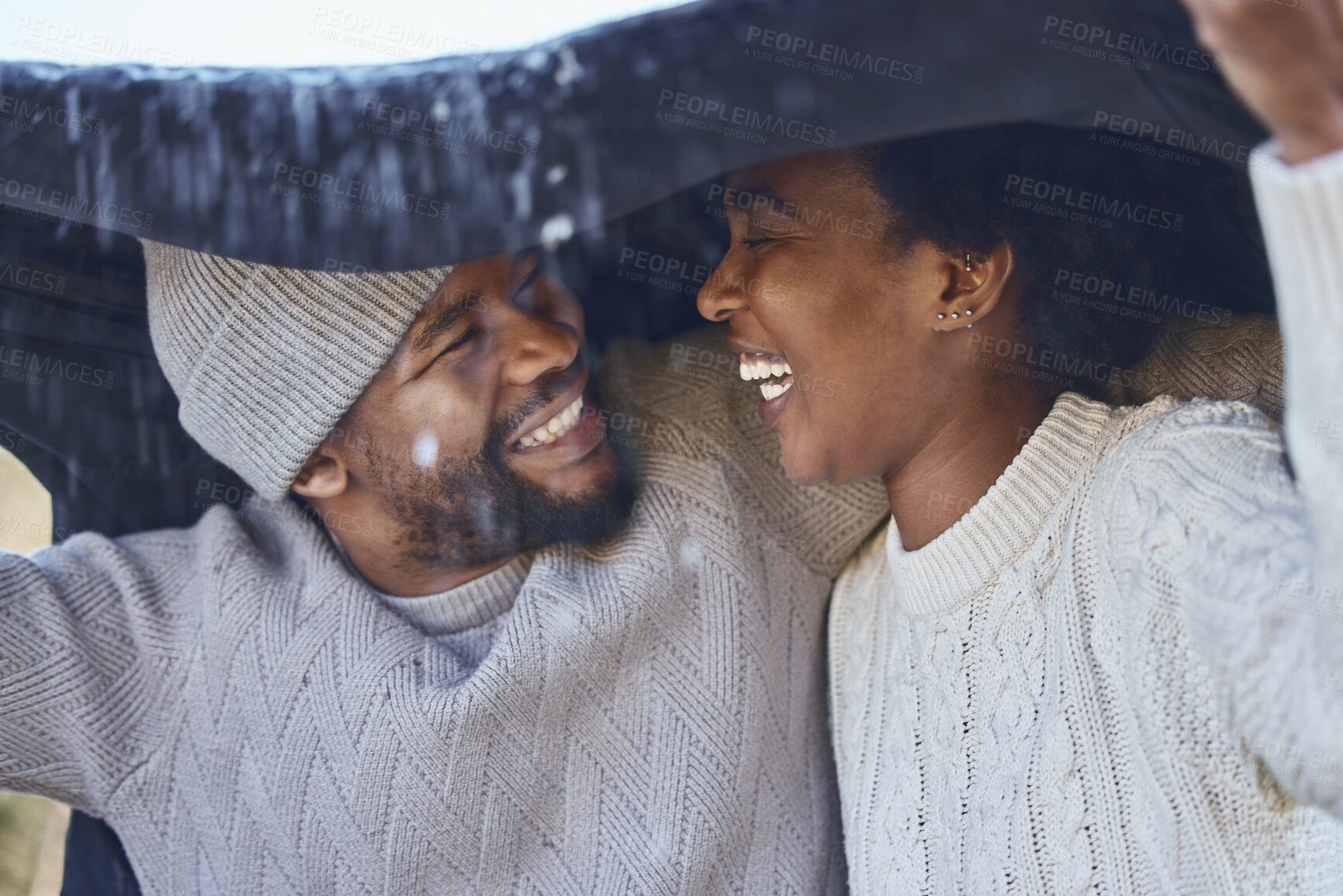 Buy stock photo Shot of a young couple protecting themselves from the rain