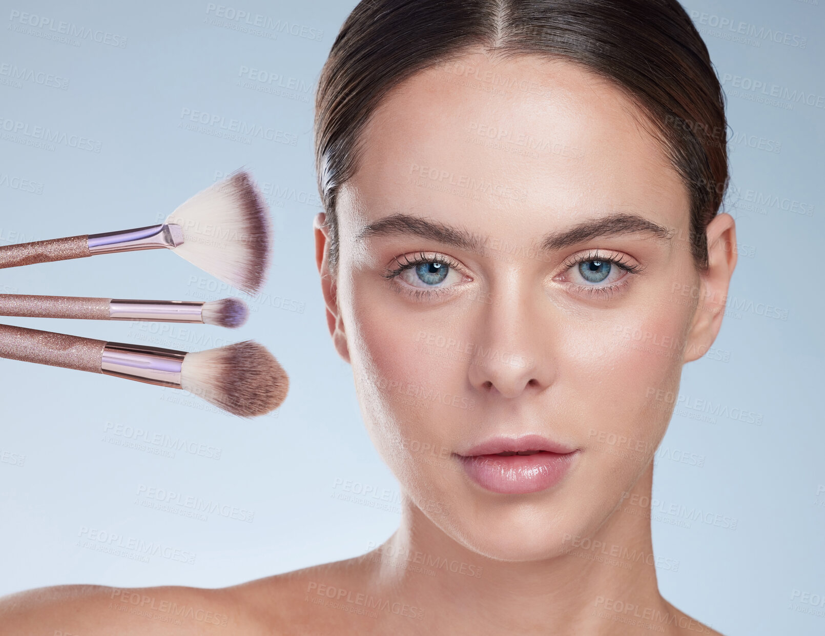 Buy stock photo Studio portrait of an attractive young woman posing with a variety of makeup brushes against a grey background