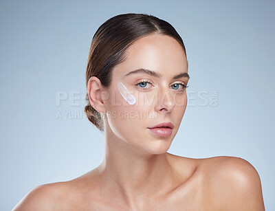 Buy stock photo Studio portrait of an attractive young woman moisturizing her face against a grey background