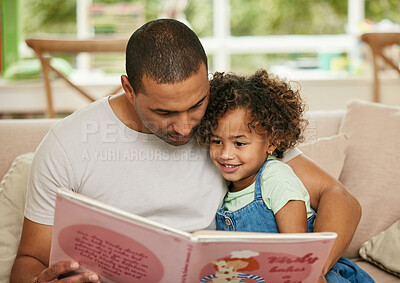 Buy stock photo Shot of a young father reading a book with his daughter at home