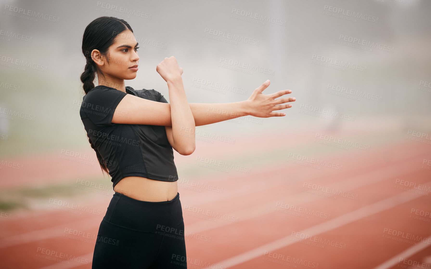 Buy stock photo Shot of an athletic young woman stretching while out on the track