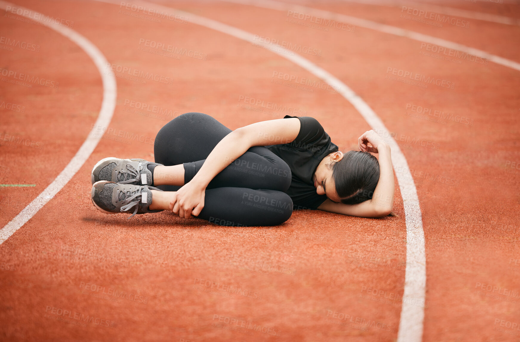 Buy stock photo Shot of an athletic young woman suffering from a sports injury while out on the track