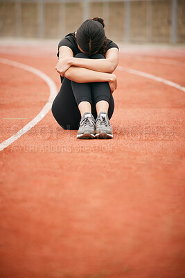 Buy stock photo Shot of a young woman looking upset while sitting on the track