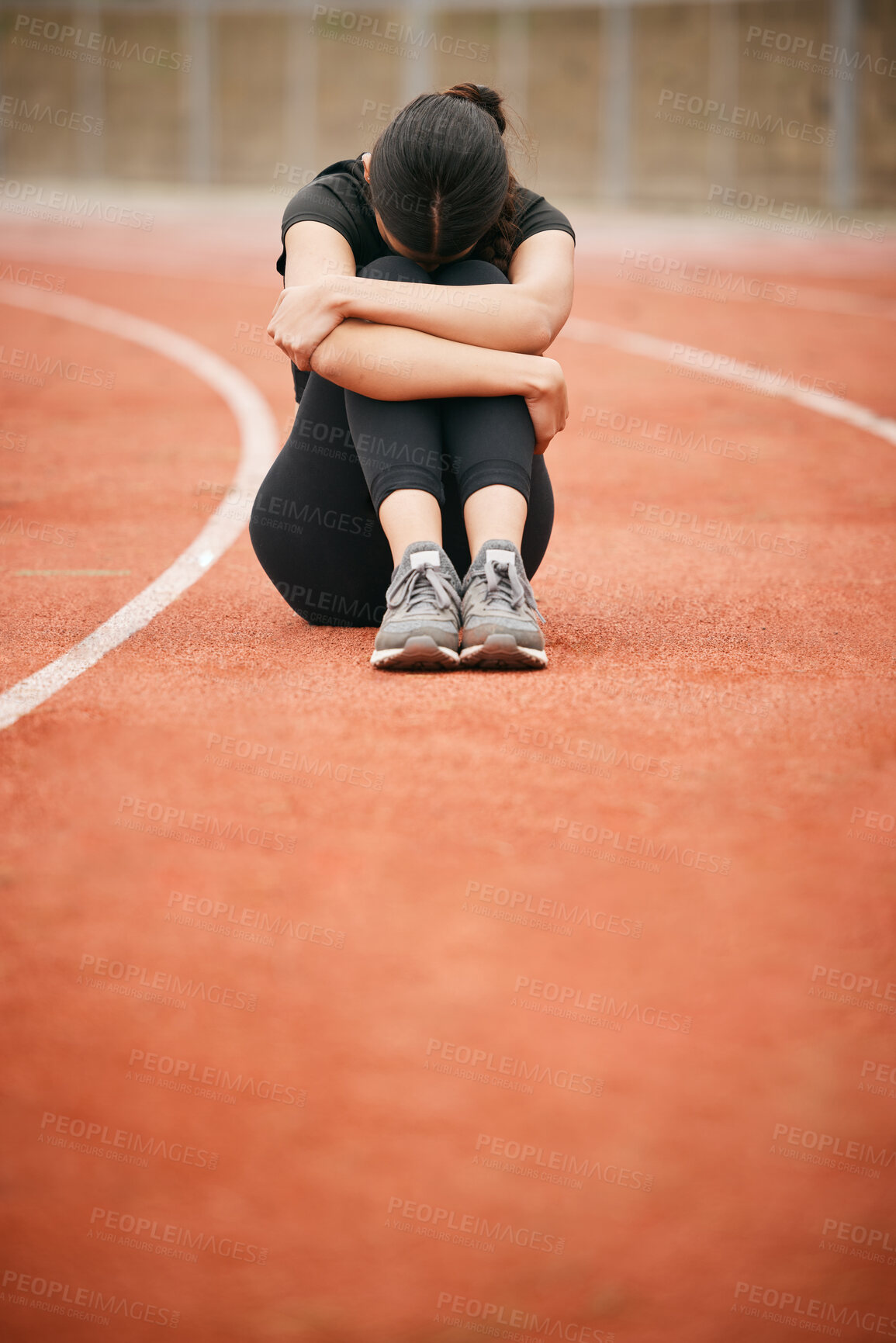 Buy stock photo Shot of a young woman looking upset while sitting on the track