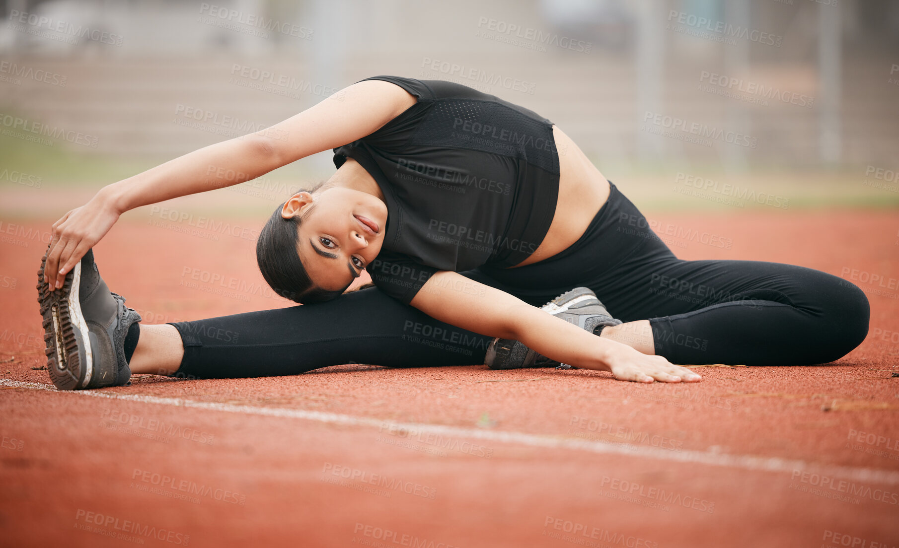 Buy stock photo Shot of an athletic young woman stretching while out on the track