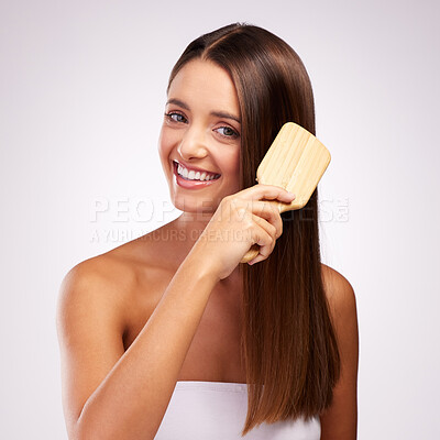 Buy stock photo Studio portrait of an attractive young woman brushing her hair against a grey background