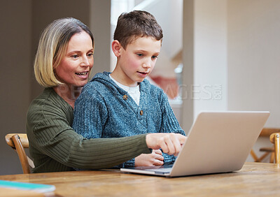 Buy stock photo Shot of a mother helping her son complete his homework using a laptop
