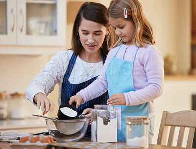 Buy stock photo Shot of a young mother helping her daughter sift flour into a bowl
