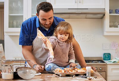 Buy stock photo Shot of a man helping his daughter frost some cupcakes