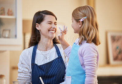 Buy stock photo Shot of a little girl playfully putting flour on her mothers face while they bake