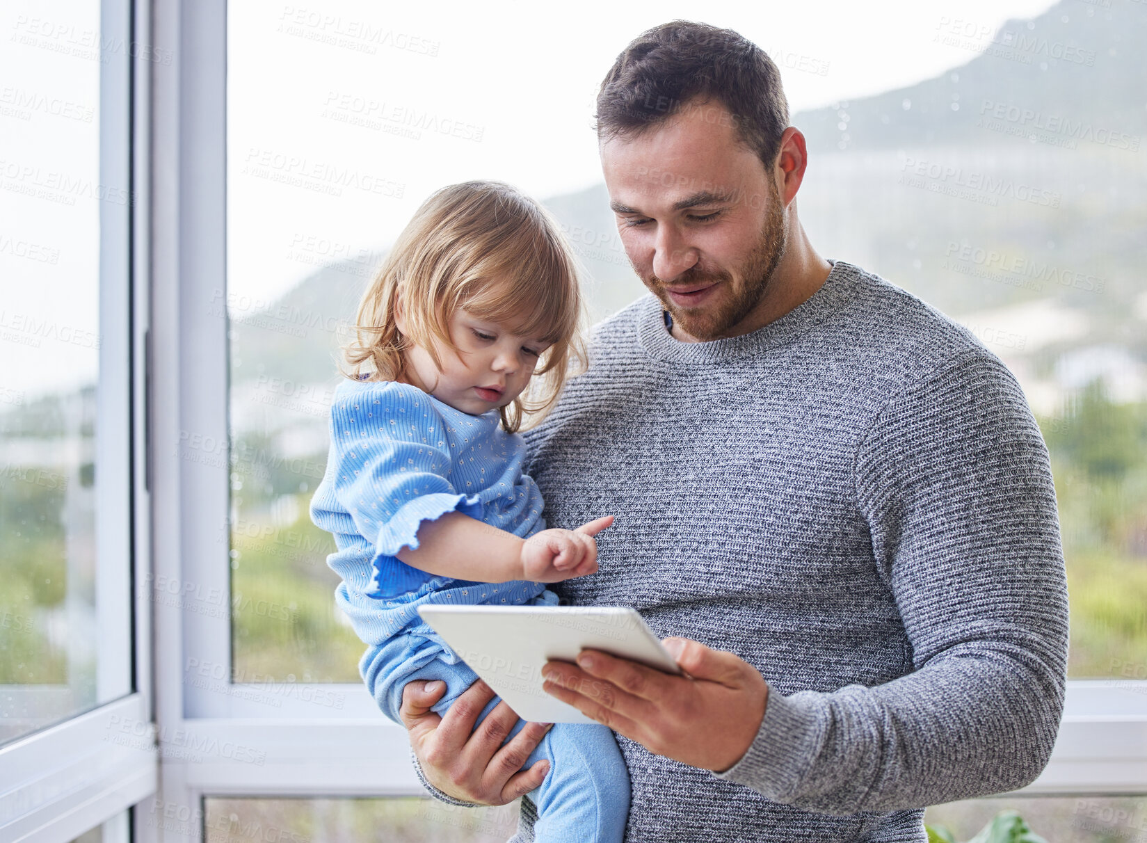 Buy stock photo Shot of a young father using a digital tablet with his daughter at home
