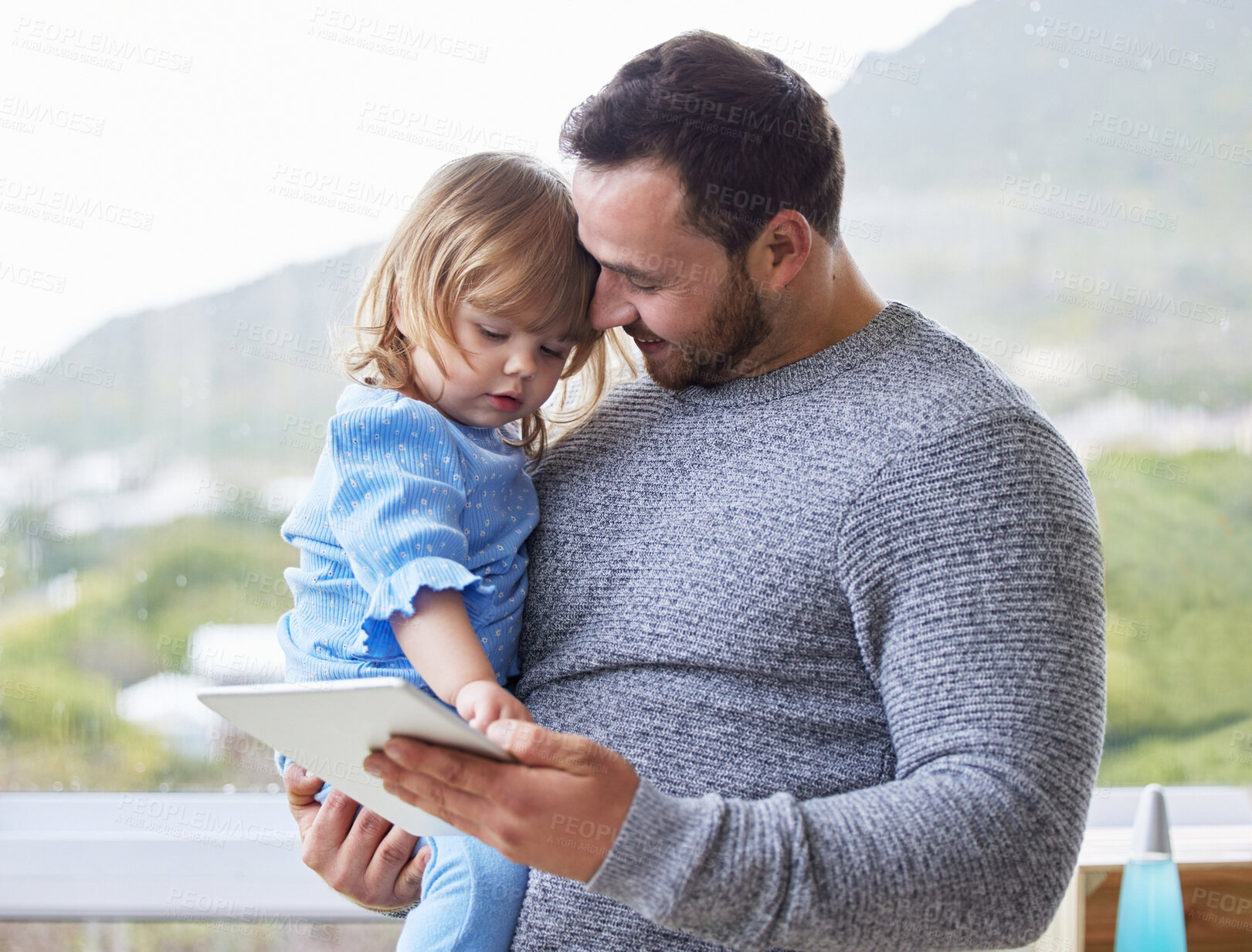 Buy stock photo Shot of a young father using a digital tablet with his daughter at home