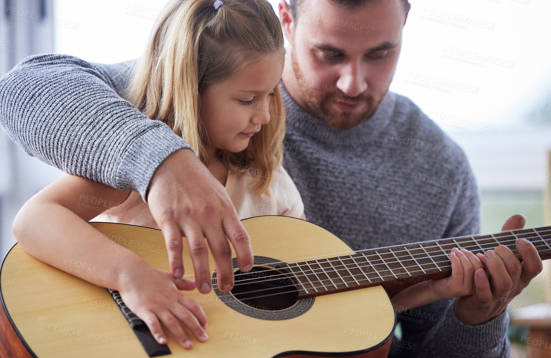 Buy stock photo Shot of a young father teaching his daughter to play the guitar at home