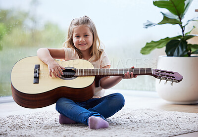 Buy stock photo Shot of a little girl playing a guitar at home