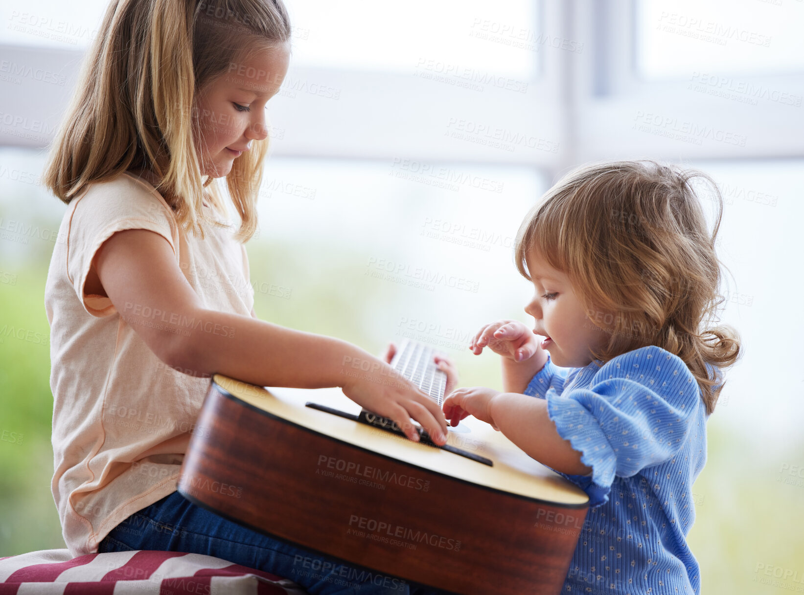 Buy stock photo Shot of two little sisters playing the guitar at home