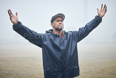 Buy stock photo Shot of a young male sports coach blowing his whistle during training