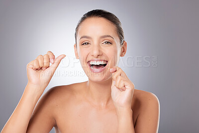 Buy stock photo Shot of a young beautiful woman flossing her teeth against a grey background