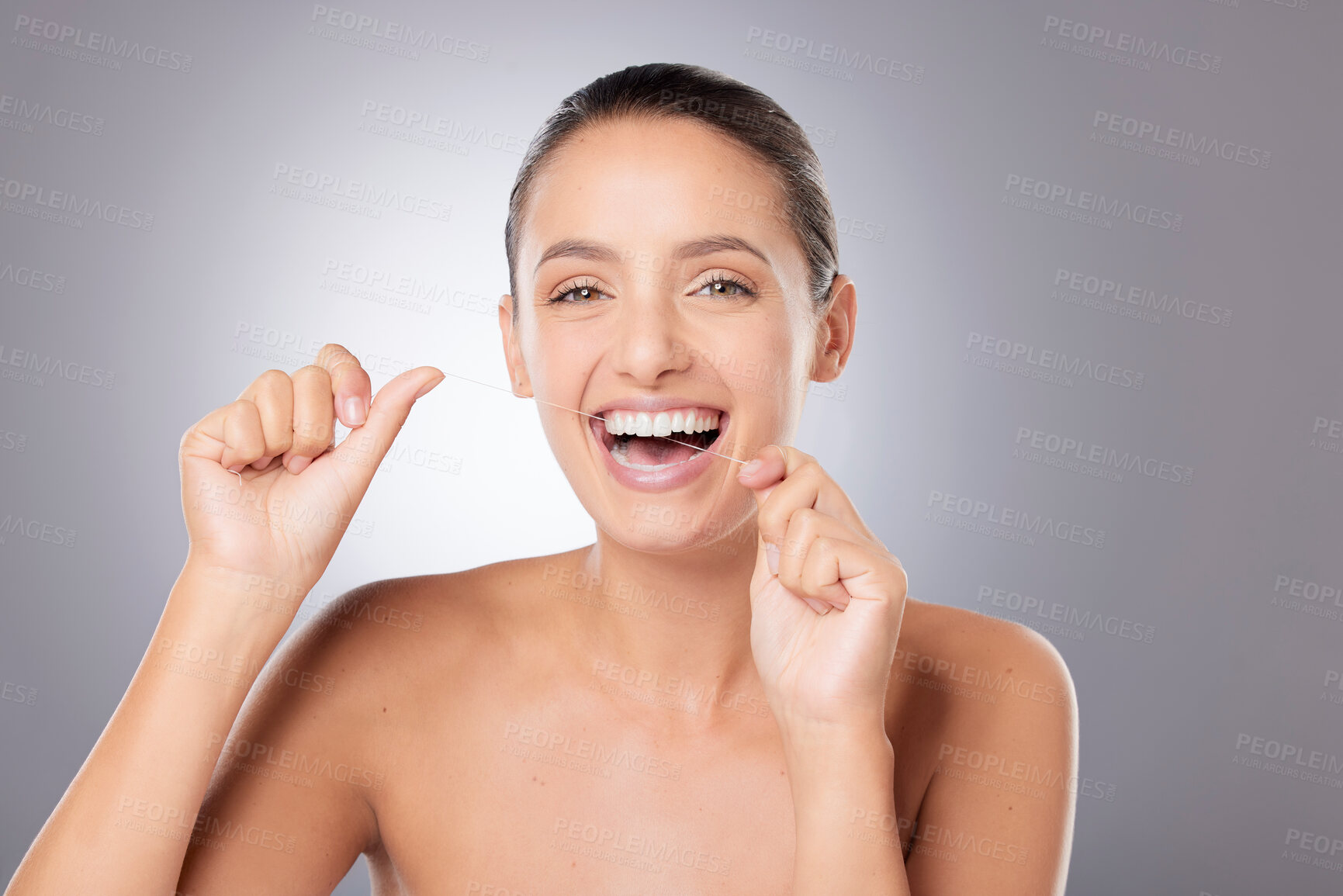 Buy stock photo Shot of a young beautiful woman flossing her teeth against a grey background