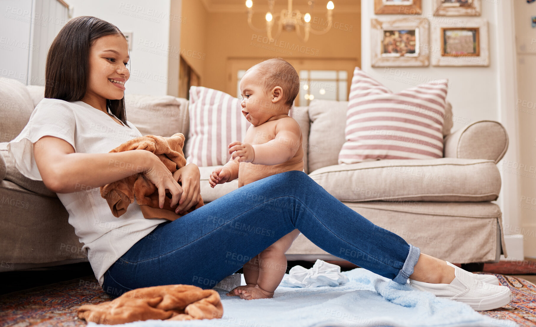 Buy stock photo Shot of a young mother dressing her son in the living room