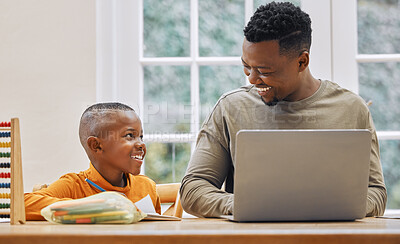 Buy stock photo Shot of a young father using a laptop while his son does homework at home