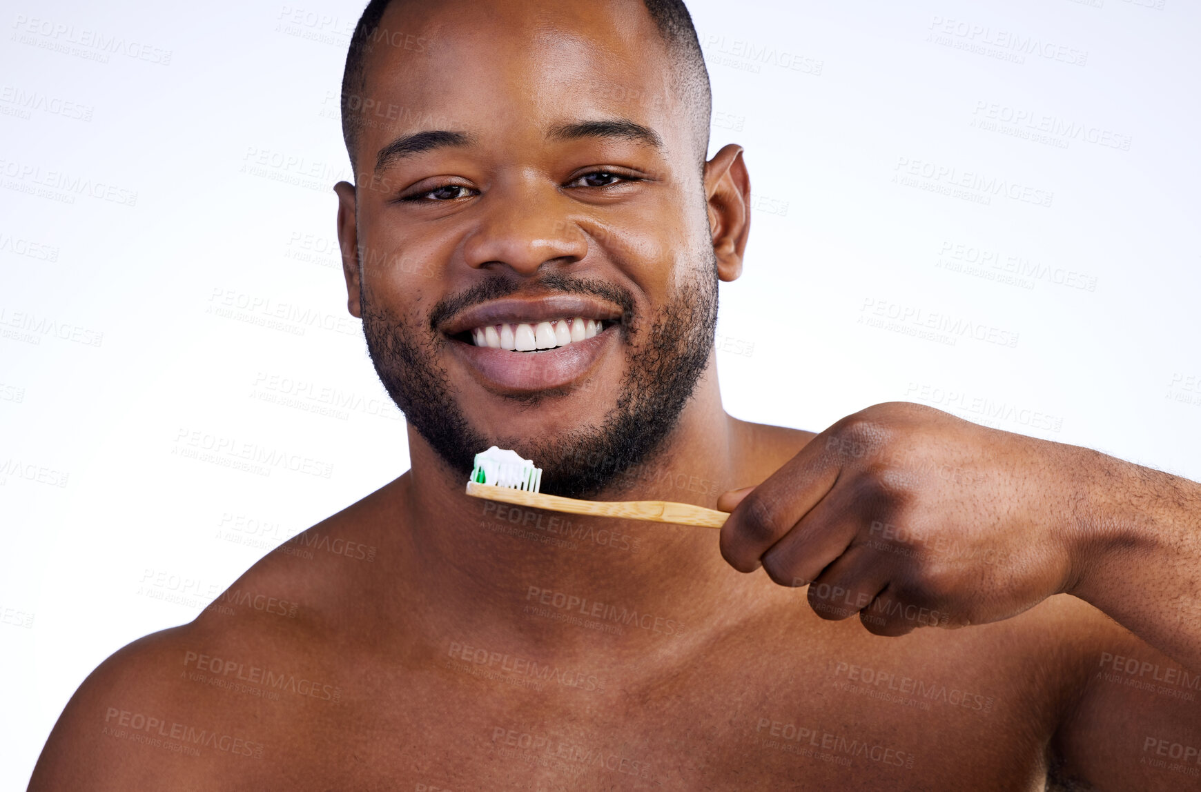 Buy stock photo Studio portrait of a handsome young man brushing his teeth against a white background