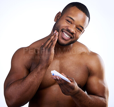 Buy stock photo Studio portrait of a handsome young man moisturizing his face against a white background