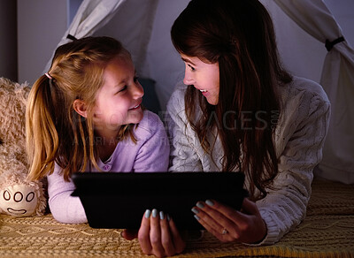 Buy stock photo Shot of a little girl and her mother watching something on a digital tablet at night