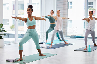 Buy stock photo Full length shot of an attractive young woman leading a yoga class in her studio and holding a warrior pose