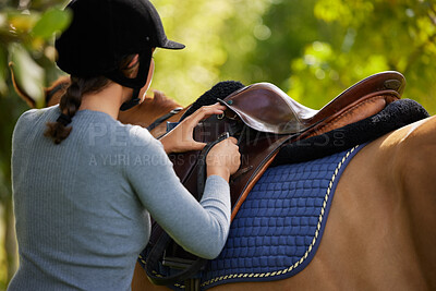 Buy stock photo Shot of a unrecognizable woman getting ready to ride her horse in nature