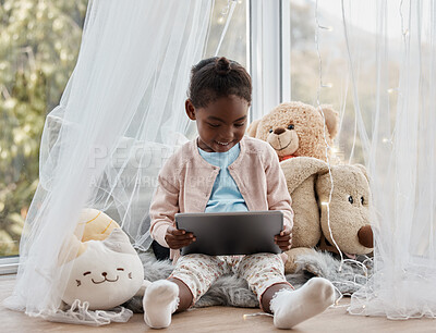 Buy stock photo Shot of an adorable little girl using a digital tablet while sitting at home