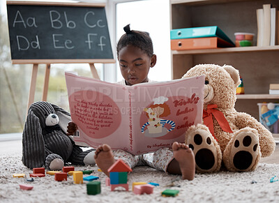 Buy stock photo Playing, house and a child reading a book, sitting and learning information. Education, studying and an African girl kid with books on the floor of a home for a story, entertainment and childhood