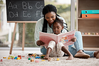 Buy stock photo Shot of a woman reading a book to her daughter while sitting at home