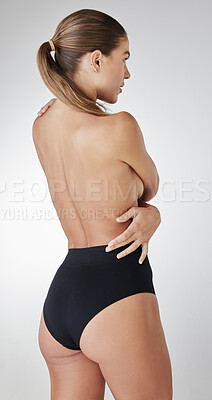 Buy stock photo Rearview studio shot of a young woman embracing her body against a grey background