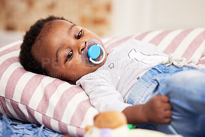 Buy stock photo Black baby, relax and lying with pacifier on bed for nap, rest or comfort of childhood at home. Young African or tired little child, cute newborn or adorable infant with dummy or soother in bedroom