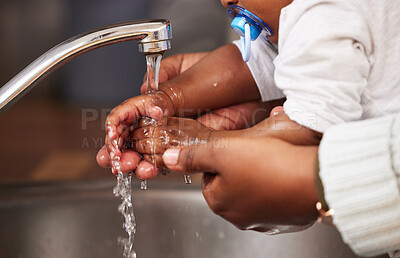 Buy stock photo Shot of an unrecognisable woman washing her baby’s hands in the sink at home