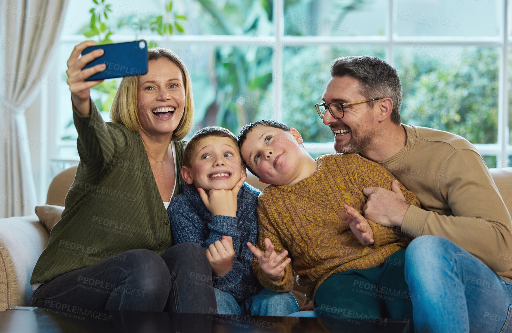 Buy stock photo Shot of a family taking a selfie using a smartphone
