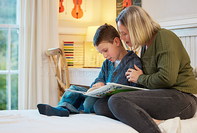 Buy stock photo Shot of a mother and son reading a book about dinosaurs together in a bedroom at home