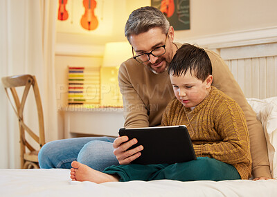 Buy stock photo Shot of a father and son using a digital tablet together in a bedroom at home