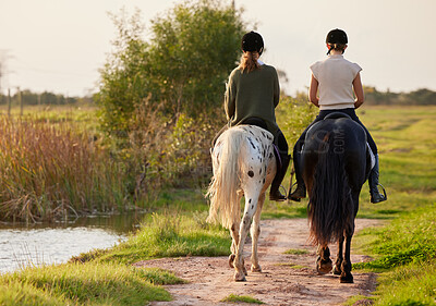 Buy stock photo Shot of two unrecognizable women riding their horses outside on a field