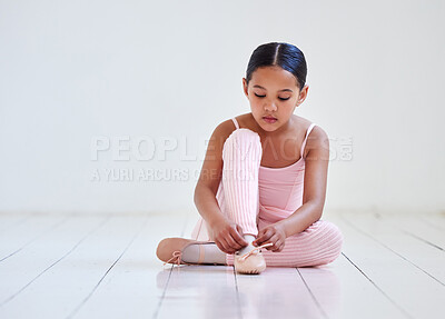 Buy stock photo Shot of a little girl putting on her shoes in a ballet studio