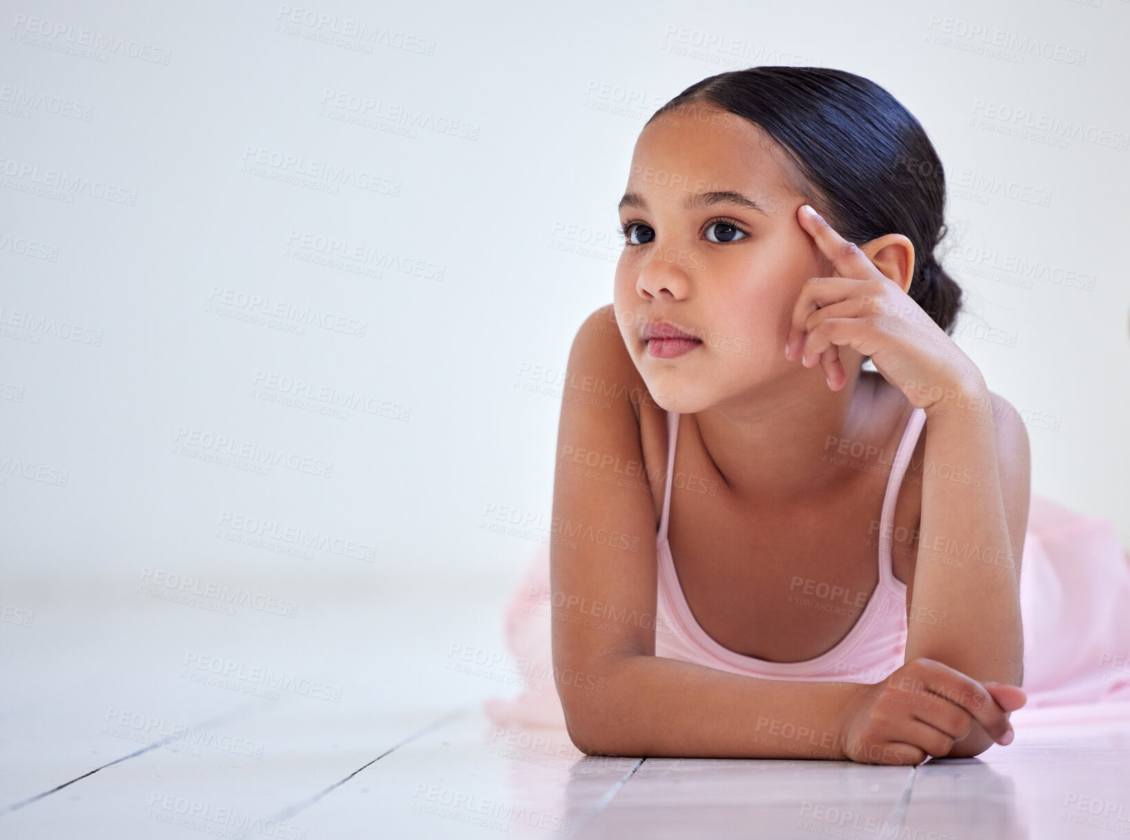 Buy stock photo Shot of a little girl looking thoughtful while lying on the floor in a ballet studio