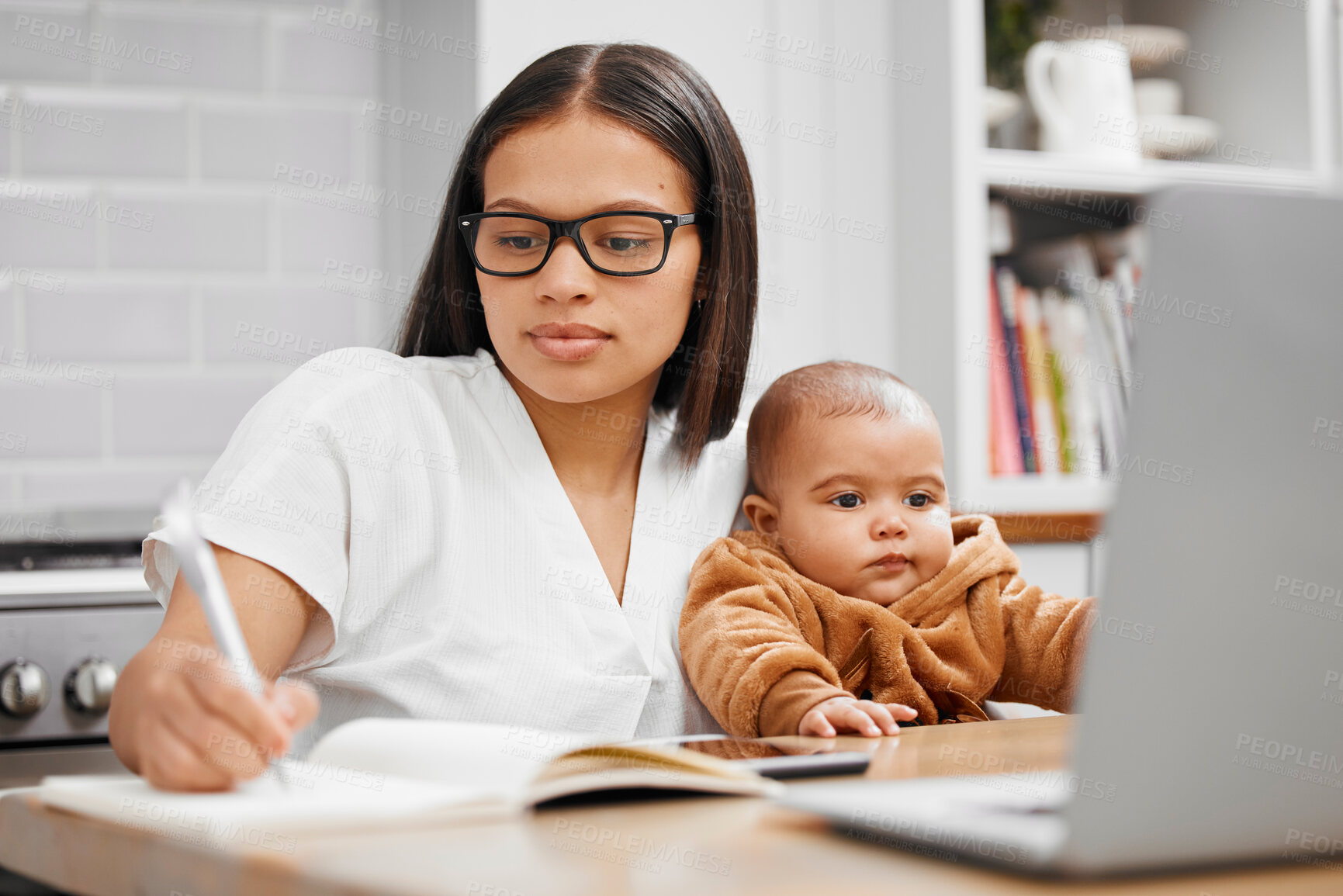 Buy stock photo Shot of a young mother writing in a notebook while holding her son at home