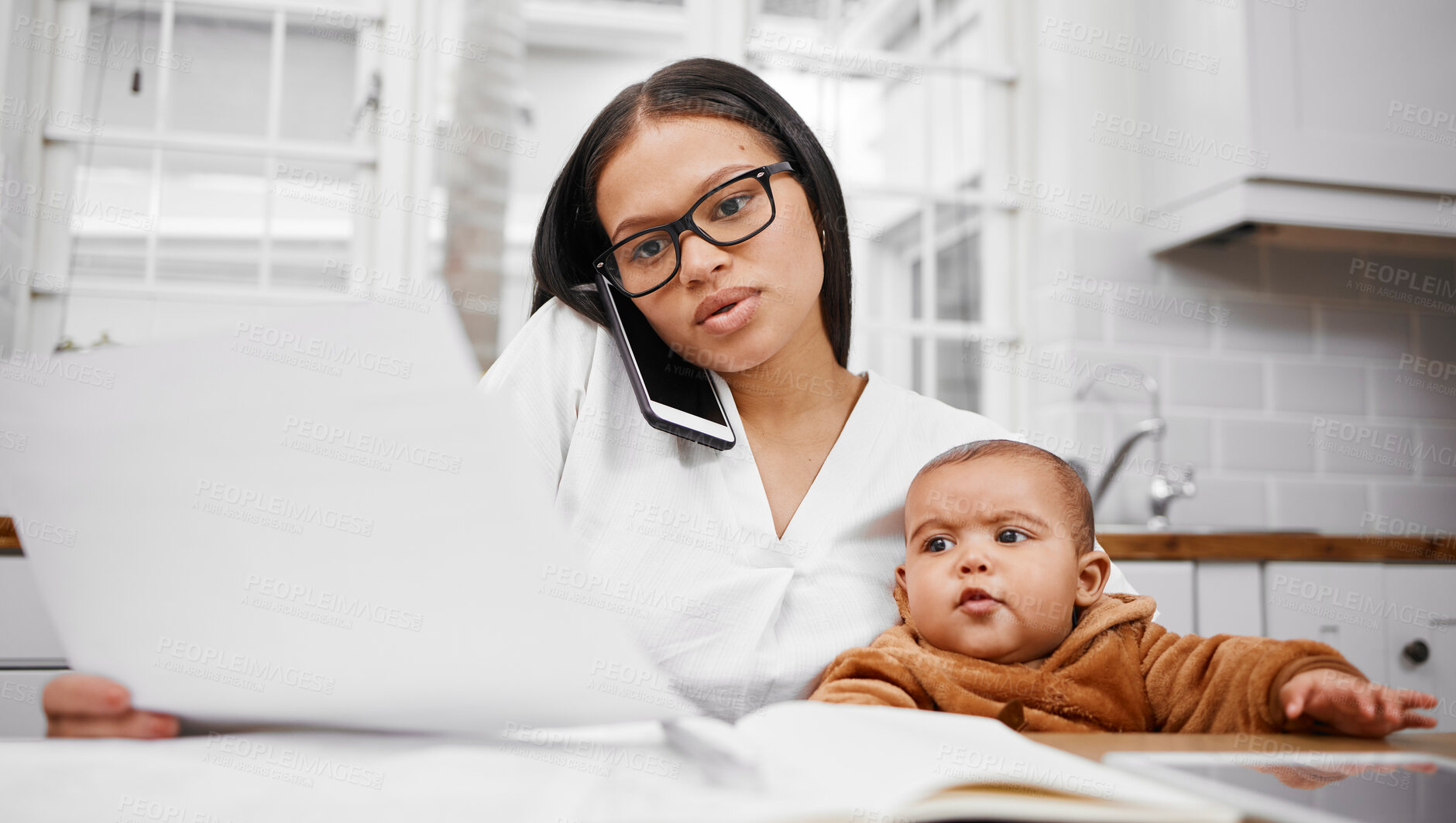 Buy stock photo Shot of a young woman going through paperwork while holding her son at home