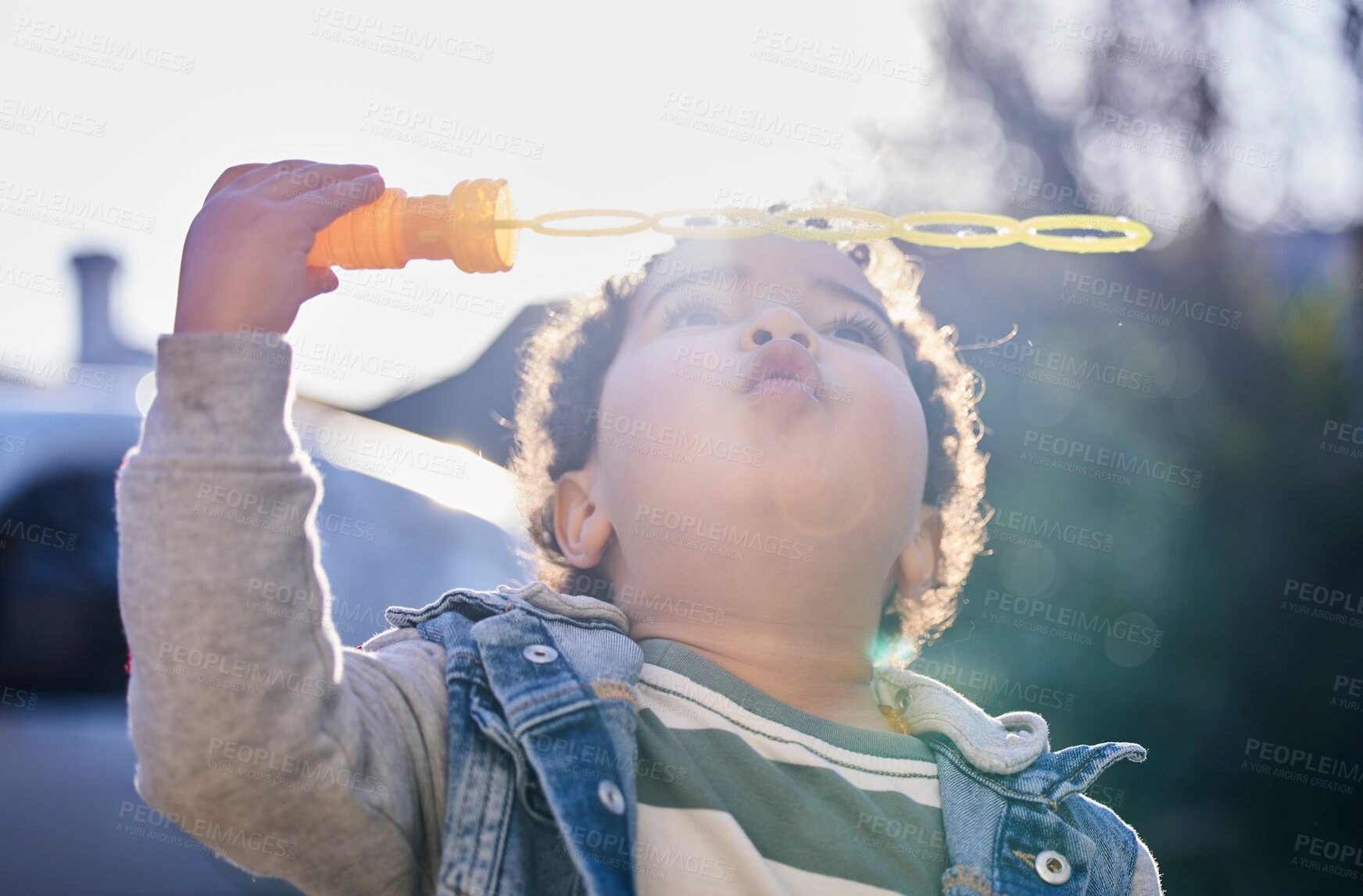 Buy stock photo Shot of an adorable little boy blowing bubbles outdoors
