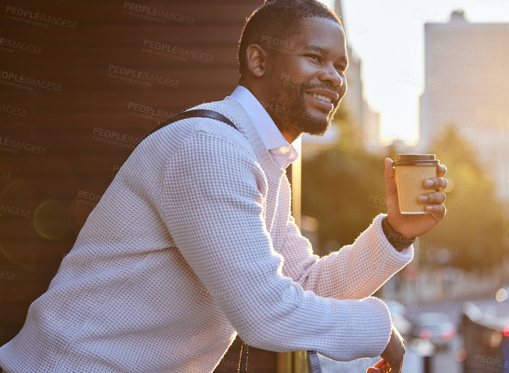 Buy stock photo Shot of a young businessman drinking coffee while standing on the balcony of an office